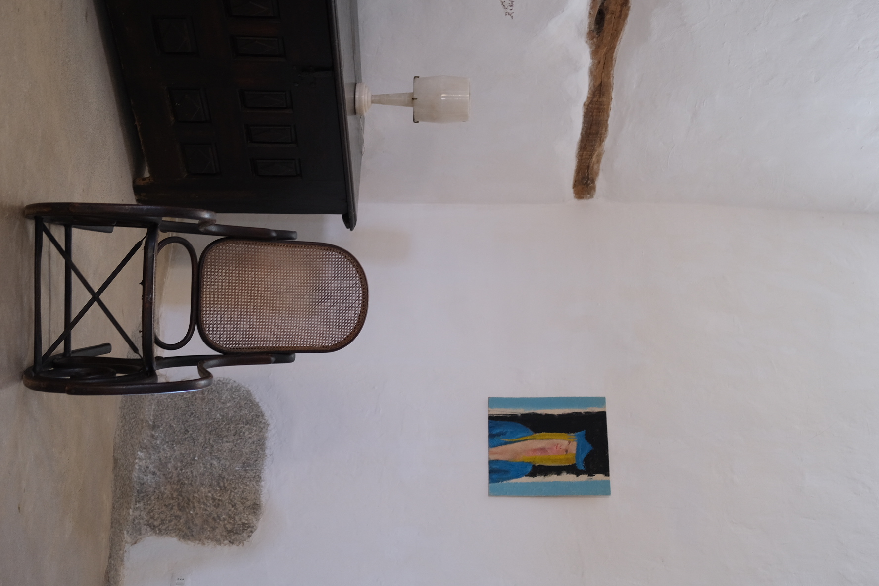 Bentwood rocking chair beside a dark chest and small painting