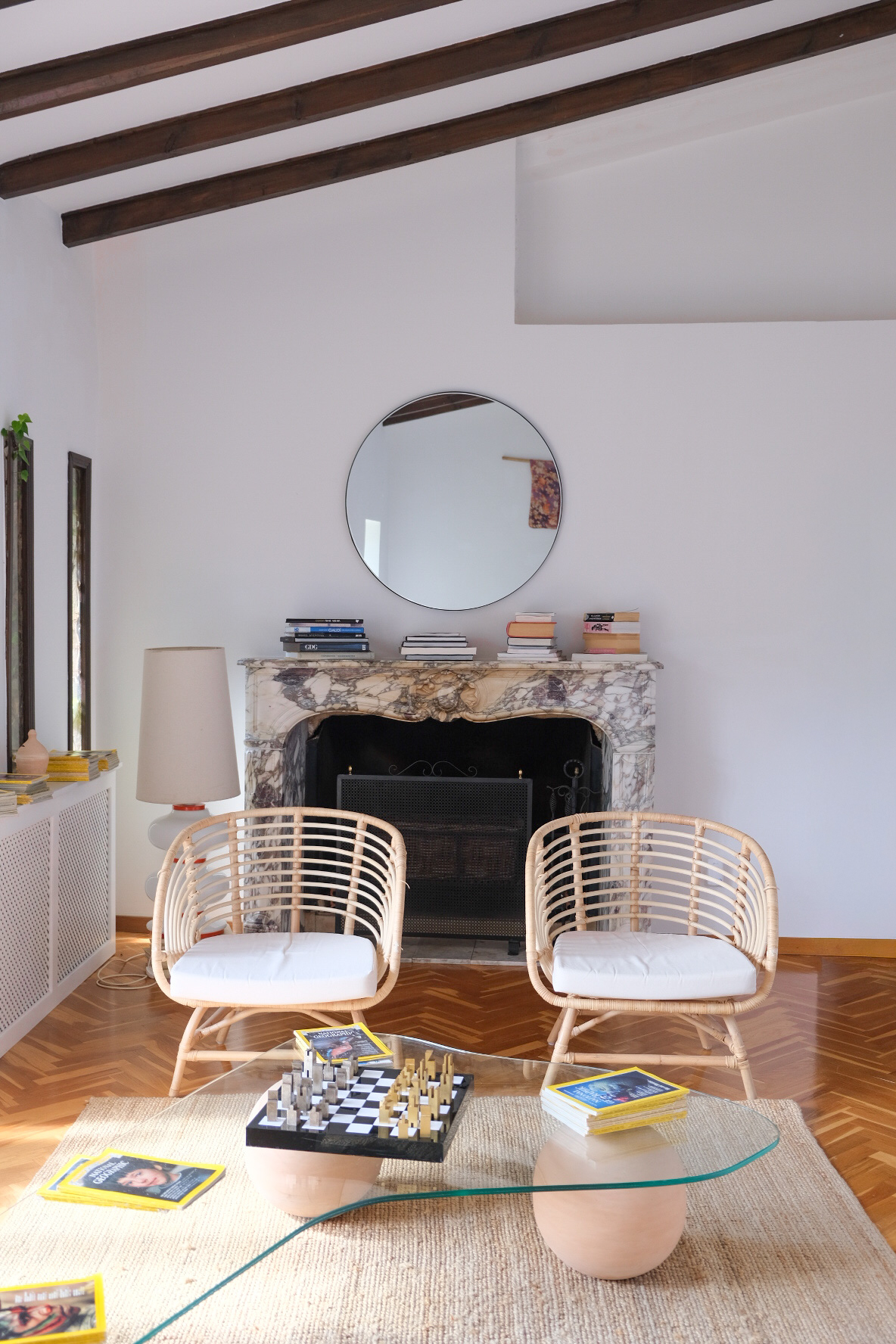 Living room with rattan chairs, fireplace and round mirror
