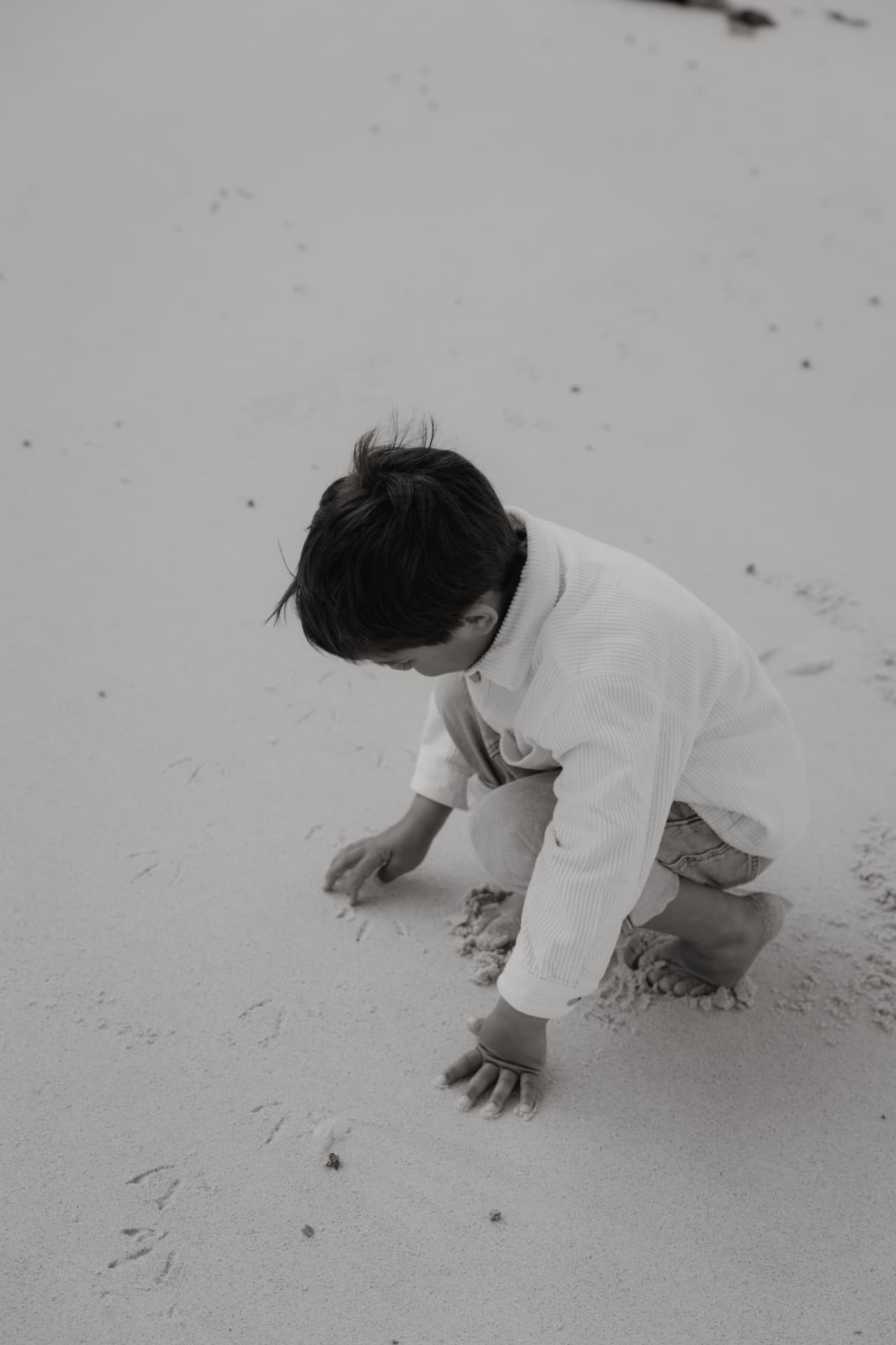 Boy crouching on the sand at the beach