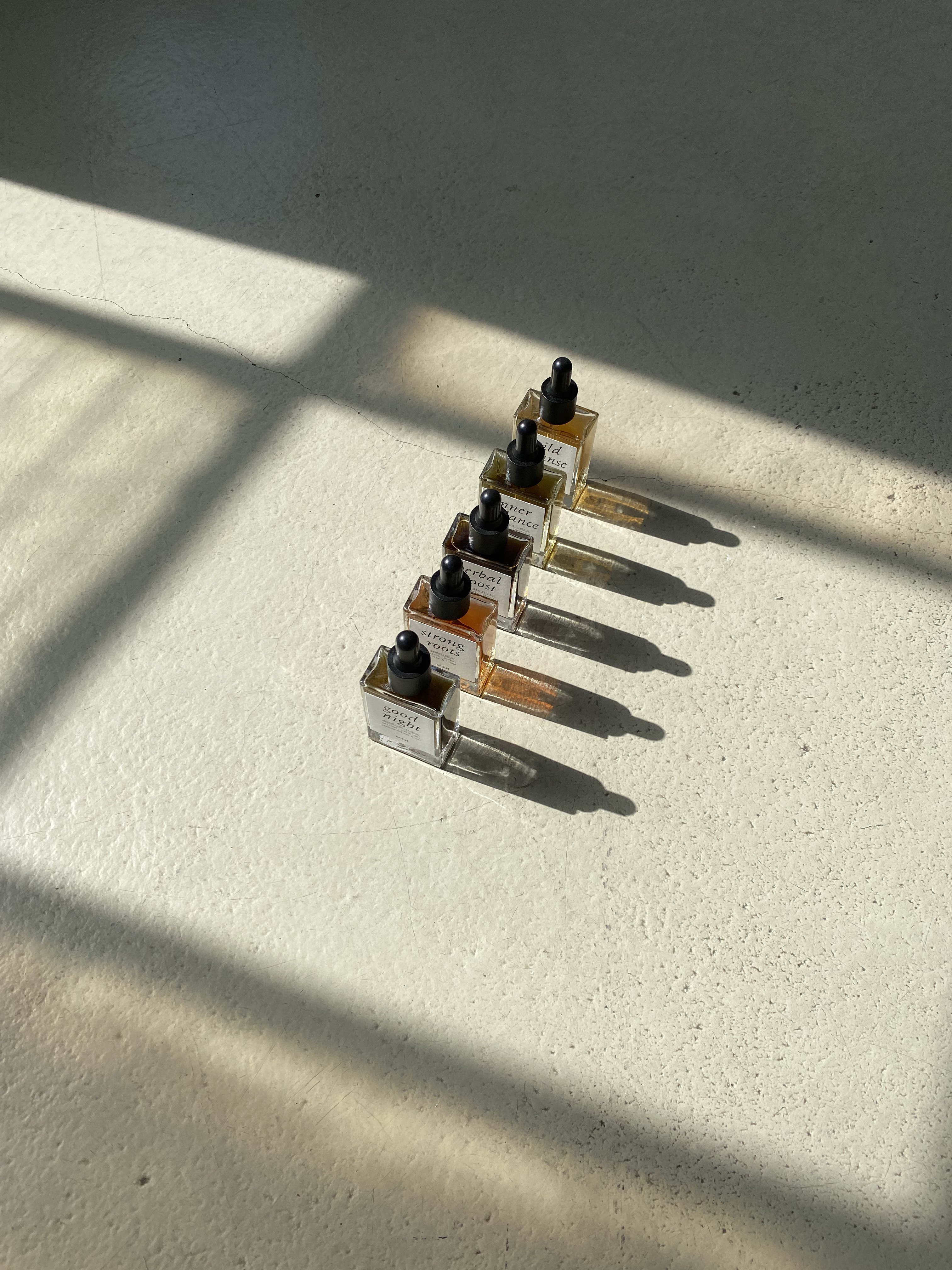 Row of glass dropper bottles of plant oils in hard sunlight
