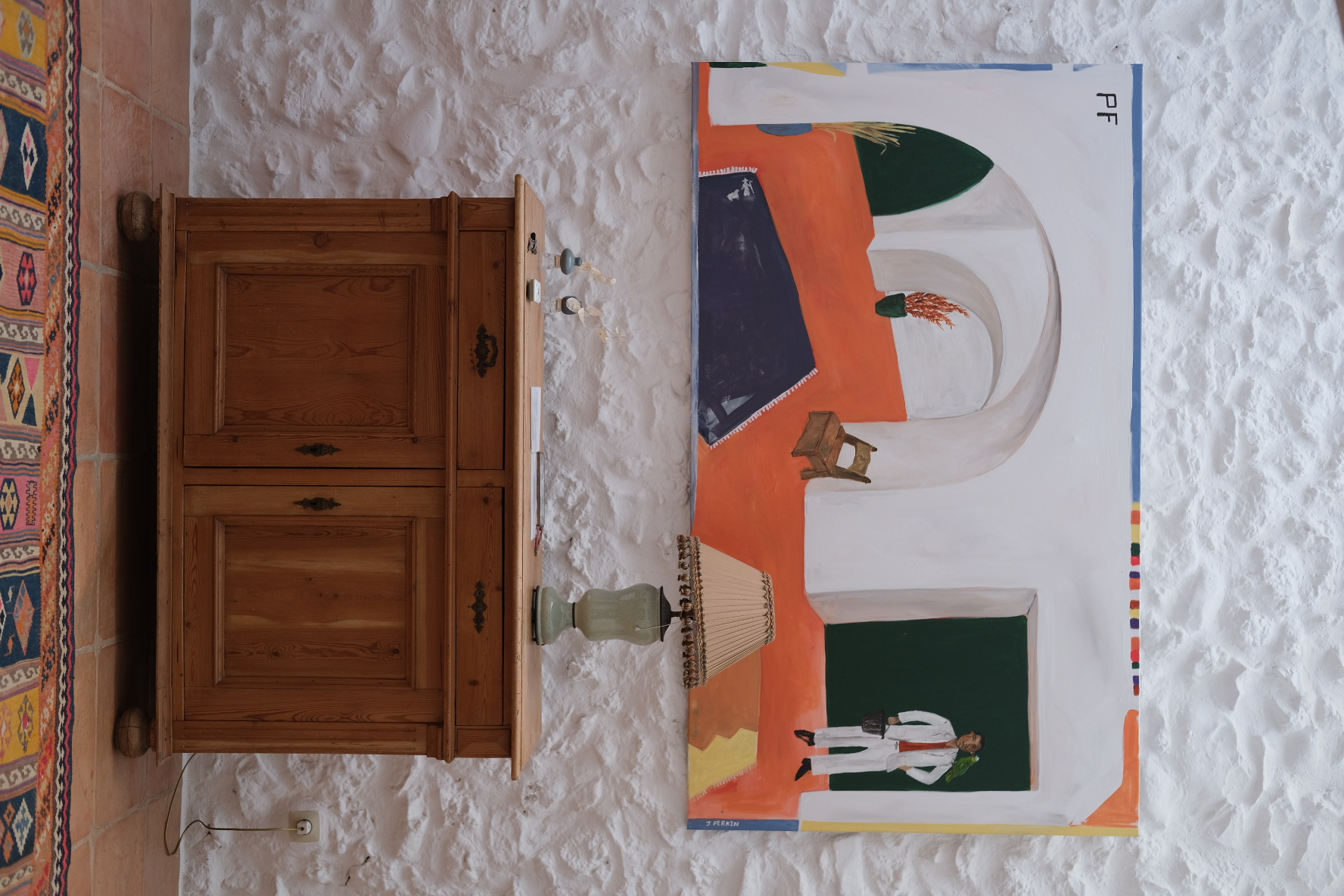 Pine sideboard beneath a large painting on a whitewashed stone wall