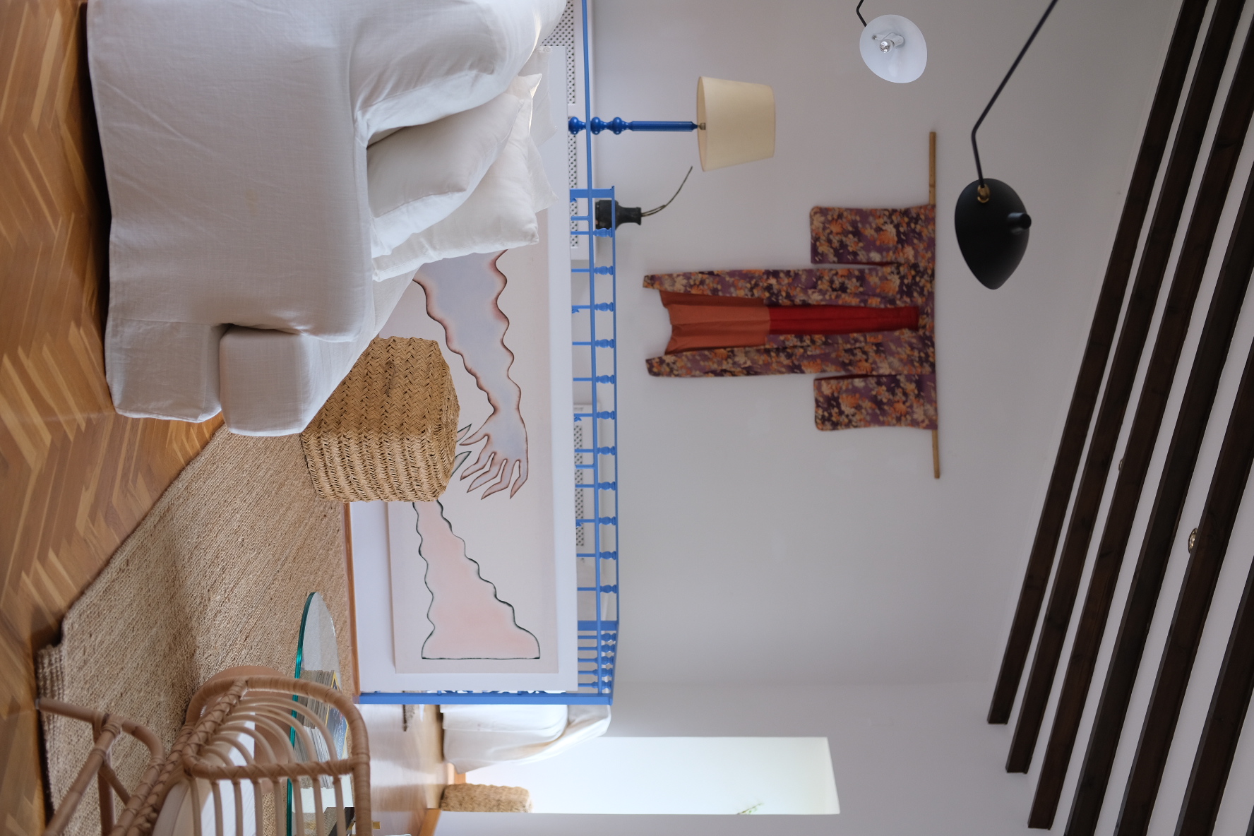Living room with white linen sofa, blue railing and textile wall hanging