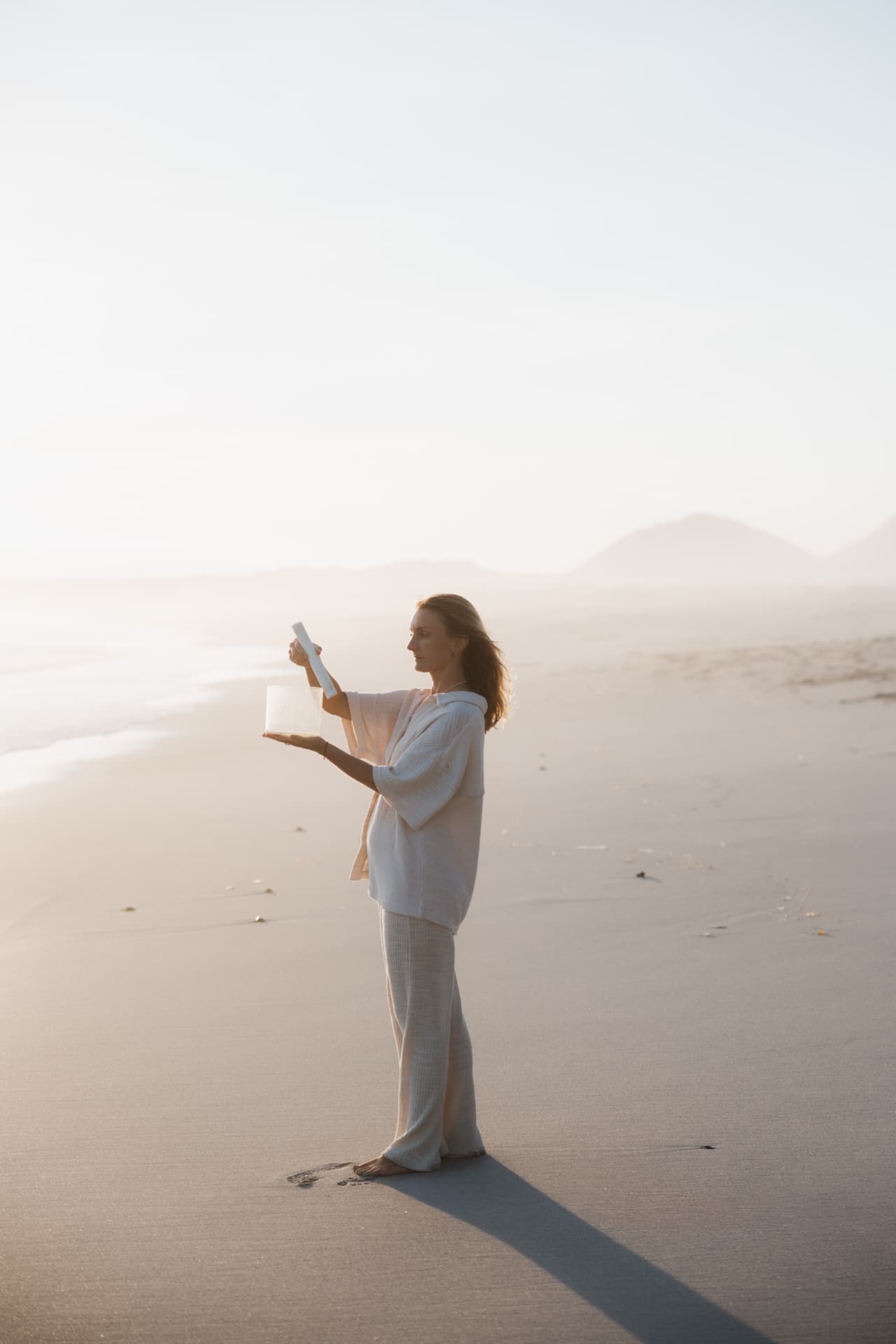 Maker holding a crystal singing bowl on a misty beach