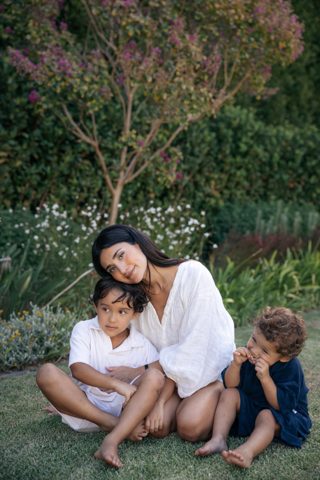 Mother and two boys resting on a grass lawn