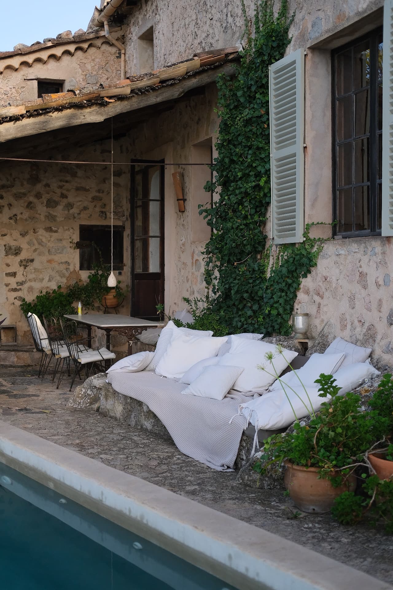Stone terrace with white linen cushions and shaded dining table