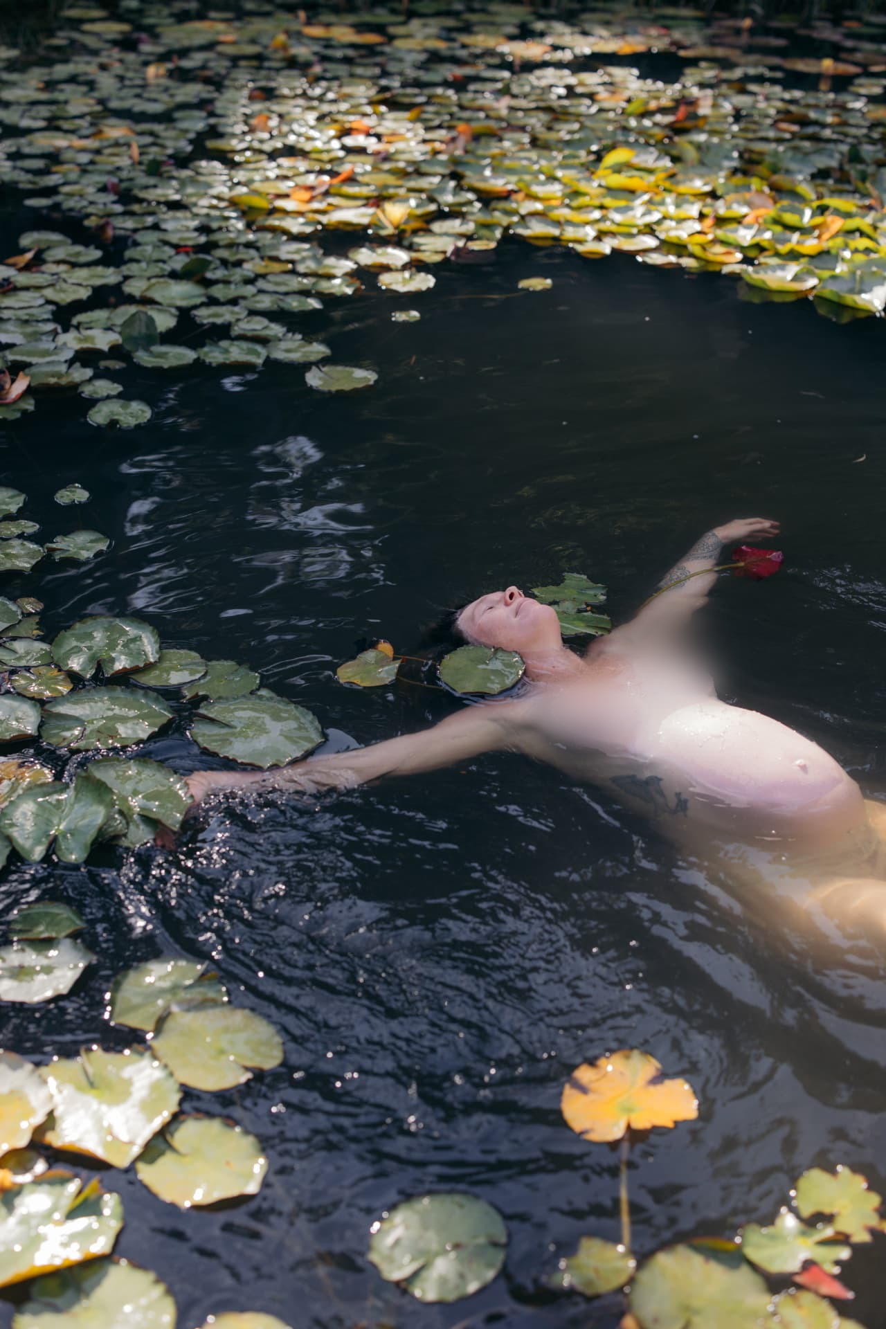 Pregnant woman floating among water lilies