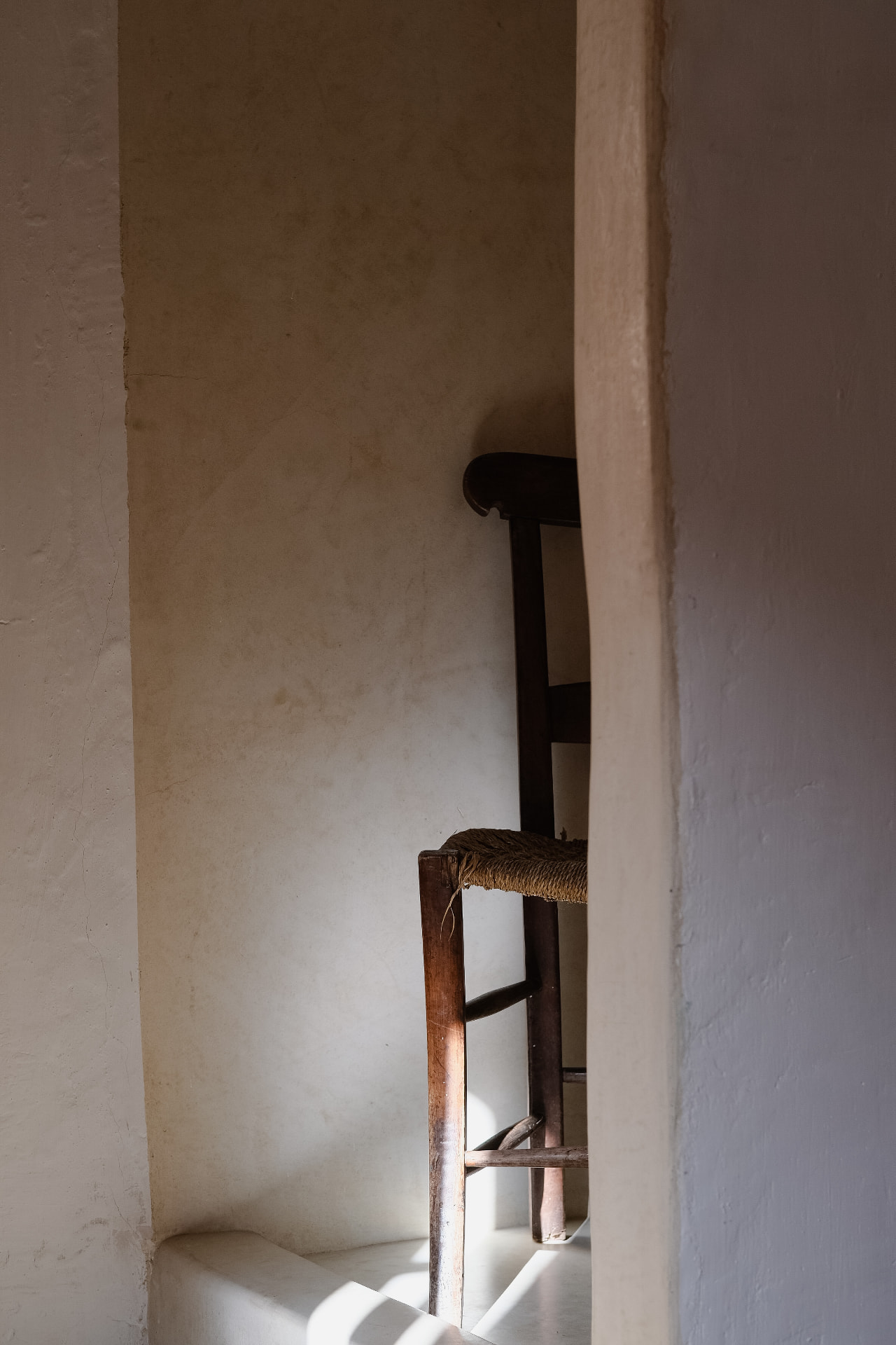 Vintage wooden chair in a sunlit arched plaster alcove