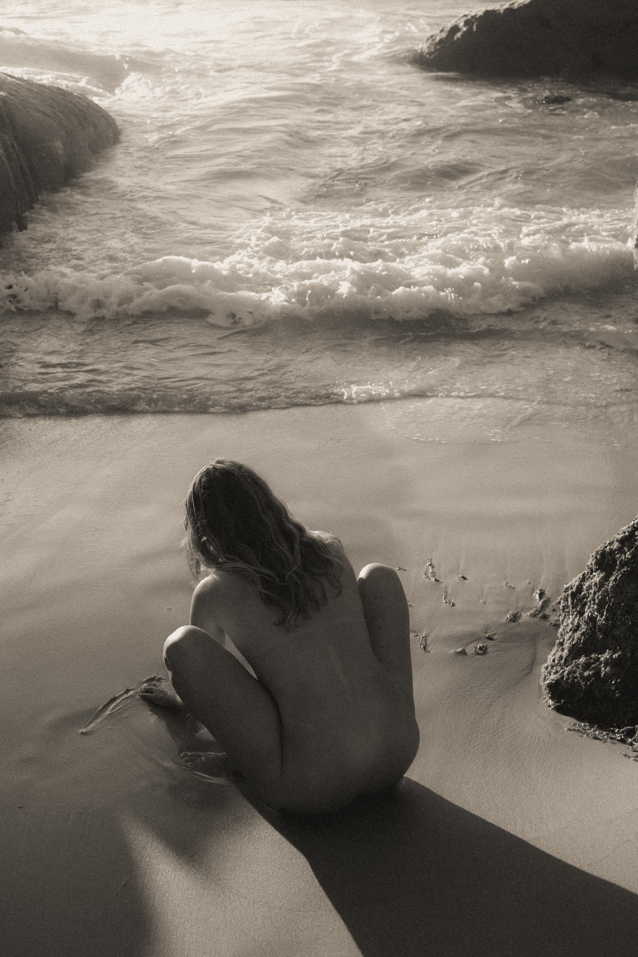 Woman sitting at the shoreline in warm evening light