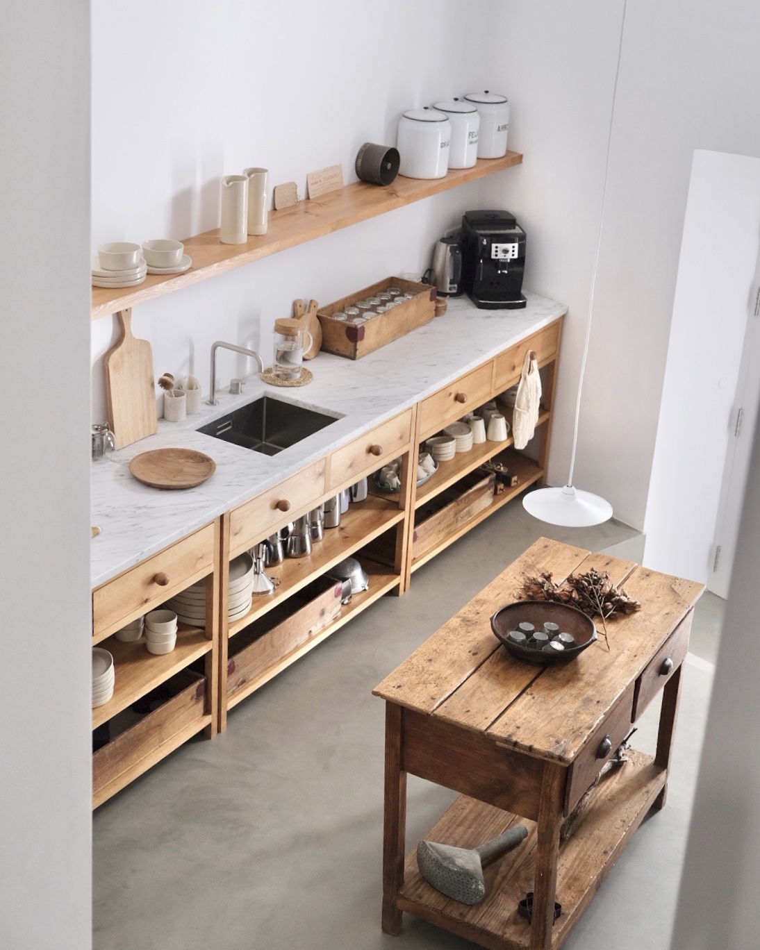 Rustic pine kitchen with marble counter, open shelves and weathered wooden table