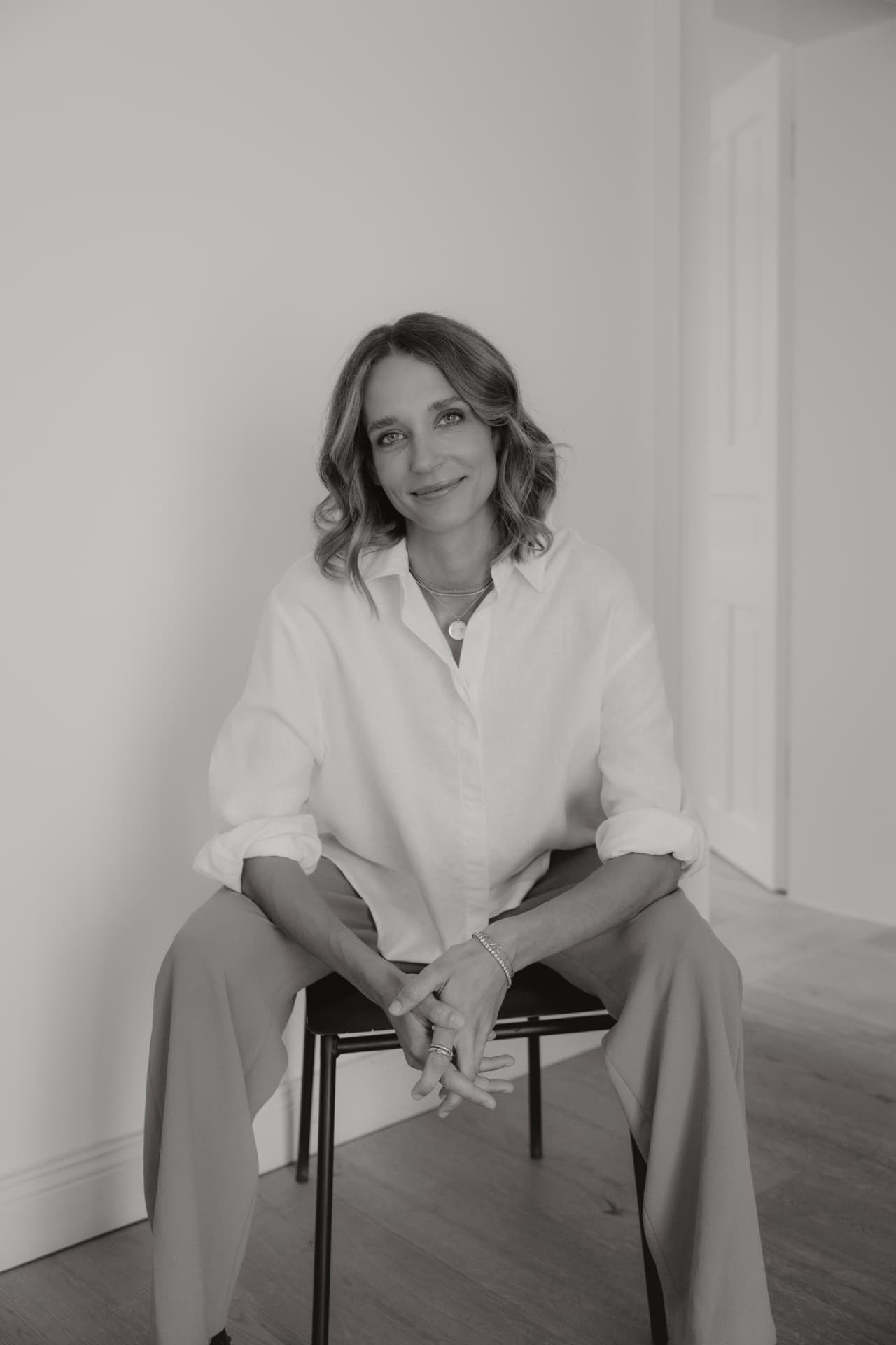 Black and white portrait of a woman sitting on a chair, smiling